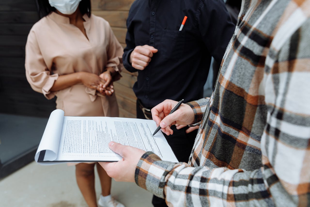 Three adults in an office setting discussing and signing a document.